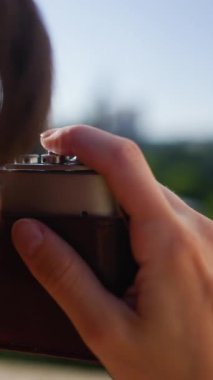 Dikey çekim. Kız düğmeye basıyor. Kameralı genç bir kız fotoğraf çekiyor. Elinde analog film kamerası olan şık ve çekici bir kadın. seyahat ve tatil.