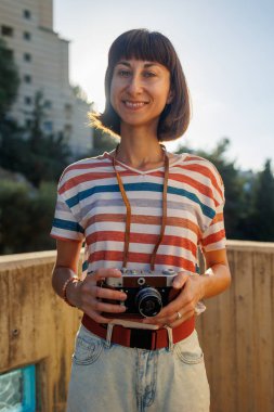 Kameralı genç bir kız. Elinde analog film kamerası olan şık ve çekici bir kadın. seyahat ve tatil.