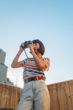 Kameralı genç bir kız. Elinde analog film kamerası olan şık ve çekici bir kadın. seyahat ve tatil.