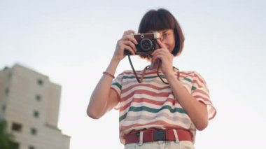 Kameralı genç bir kız. Fotoğrafçı kamerayı kurar ve fotoğraf çeker. Film kamerası olan şık bir kız. Film kamerası kapat. Maceralar ve seyahat.