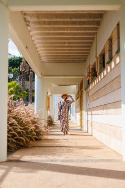 Açık havada, sokakta yürüyen, elbise ve şapka giymiş güzel esmer bir kadının uzun bir portresi. moda ve tarz kavramı.