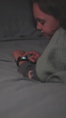 Dikey çekim. Çocuklar yatmadan önce çalar saati kurdular. akıllı saat.