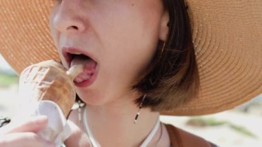 Şehir caddesinde dondurma yiyen güzel genç bir kadın, yakın plan.