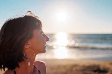 Yaz havası. Kumsalda güzel bir esmerin portresi. Genç mutlu kız gülümsüyor.