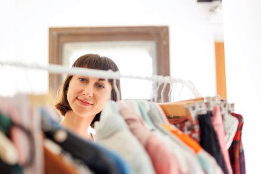 Evde gardırop ya da giyim mağazasının soyunma odası. Genç bir kadın evdeki ya da mağazadaki dolabından şık bir kıyafet seçer. Kız ne giyeceğini düşünüyor..