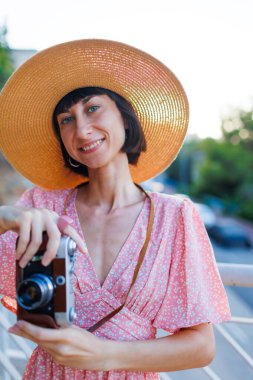 Şapkalı genç kız. Yaz havası. Kameralı kadın fotoğrafçı dışarıda fotoğraf çekiyor. Fotoğrafçı objektife nişan alır ve çekim işleminden zevk alır. seyahat ve tatil.