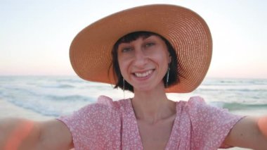 Kumsalda gülümseyen ve selfie çeken mutlu genç bir kadın. Sevimli kız sokakta akıllı telefon kullanarak selfie çekiyor. Sahilde güzel bir kız.