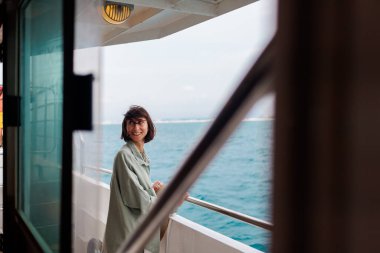 Kız bir yolcu gemisinin güvertesinde duruyor. Kız seyahat ediyor. Genç ve güzel bir esmer yat ile seyahat ediyor. seyahat ve macera.