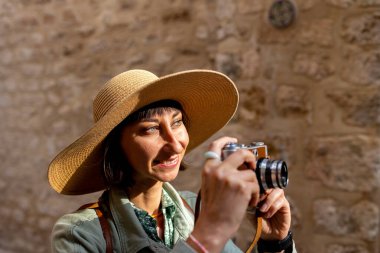 Şapkalı güzel bir kadın dışarıda analog kamera kullanarak fotoğraf çekiyor. Arap ülkelerine gitmek. seyahat ve tatil.