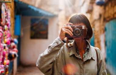 Güzel bir kadın dışarıda analog kamera kullanarak fotoğraf çekiyor. Arap ülkelerine gitmek. seyahat ve tatil.