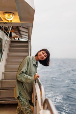 Yaz seyahati sırasında yolcu gemisinde tatil yapan bir kadın. Feribotun açık balkonunda dinlenen bir turistin silueti. Bir kız bir yolcu gemisinin güvertesinde durur ve denize bakar.