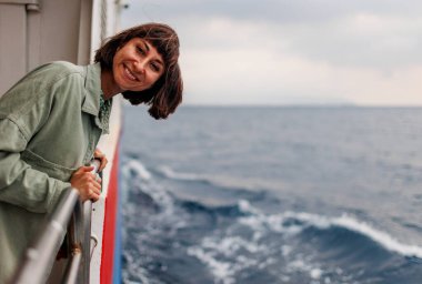 Yaz seyahati sırasında yolcu gemisinde tatil yapan bir kadın. Feribotun açık balkonunda dinlenen bir turistin silueti. Bir kız bir yolcu gemisinin güvertesinde durur ve denize bakar.