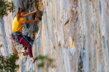  Kız kayaya tırmanıyor. Dağcı kız. Bir olimpiyat sporu olarak kaya tırmanışı. Bir kadın doğada spor yapar.
