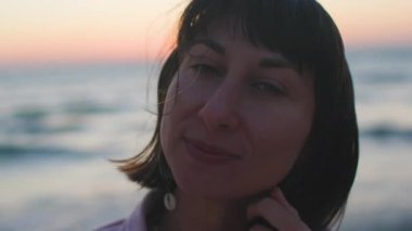 Sahildeki kız. Kumsalda dinlenen mutlu genç kız. Deniz kenarında gün batımı. Kız kumsalda duruyor. Kumsalda dinlenmek. Yaz havası.