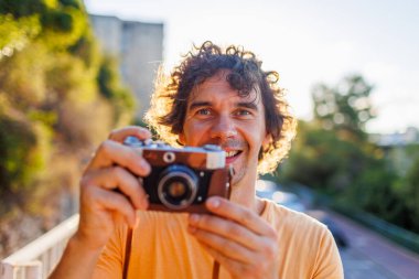 Sarı tişörtlü, elinde kamera olan yakışıklı, şık bir gencin portresi. film kamerası.