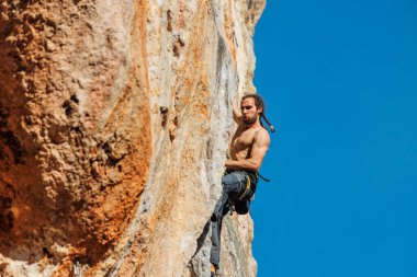 Erkek kaya tırmanışçısı bir kayaya tırmanır. Spor ve açık hava eğlencesi. Sportif adam kaya tırmanışı yapıyor. ekstrem spor