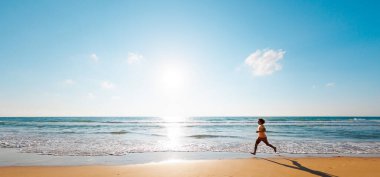 Aktif adam koşuyor. Sağlıklı bir yaşam tarzı. Bir adam deniz kenarında yalınayak koşuyor. Genç bir koşucu şafakta boş bir plaj boyunca koşar. Denize yakın koş..