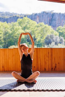 Sokakta esneme hareketleri yapan genç bir kadın. Sağlıklı bir yaşam tarzı. Spor giyimli güzel bir kız yoga yapıyor..