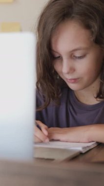 Dikey çekim. Öğrenci not defterindeki ödevi tamamlar. Okulda online öğrenim.