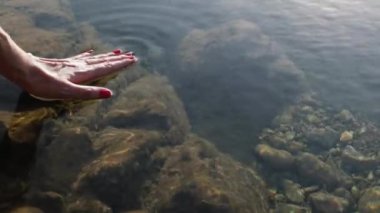 Ellerin gölün sakin yüzeyine değdi. Kadının eli suyun sakin yüzeyine dokunuyor..