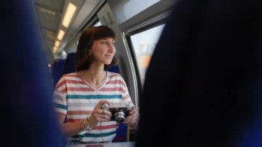 Tren yolculuğu. Genç bir kadın tren yolculuğundan zevk alıyor ve kamerasıyla güzel turistik noktaların fotoğraflarını çekiyor. Film kamerası. Kız film kamerası kullanıyor..