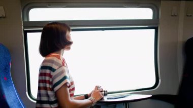 Tren yolculuğu. Genç bir kadın tren yolculuğundan zevk alıyor ve kamerasıyla güzel turistik noktaların fotoğraflarını çekiyor. Film kamerası. Kız film kamerası kullanıyor..