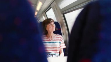 İyi yolculuklar. tren yolcusu. Tren yolculuğu. Genç ve güzel bir kadın tren yolculuğundan zevk alıyor, pencerenin kenarında oturuyor ve pencereden dışarı bakıyor..