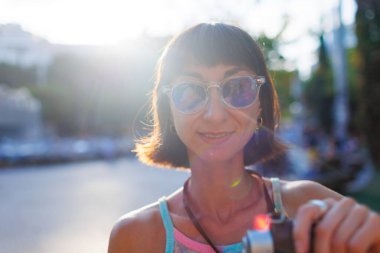 Kameralı kadın fotoğrafçı dışarıda fotoğraf çekiyor. Genç bir bayan fotoğrafçı objektife nişan alır ve çekim sürecinden zevk alır.. 