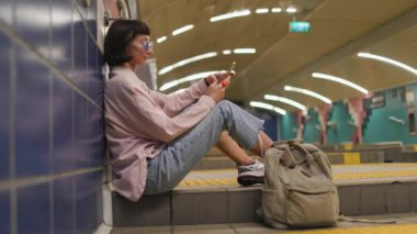 Toplu taşıma araçlarıyla seyahat etmek. İstasyonda tren bekleyen genç bir kadın. Metrodaki kız. Metroda sırt çantalı şık elbiseli genç bir kız. Modern kadın yaşam tarzı.