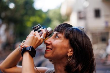 Şehirde dolaşan ve kamerayla fotoğraf çeken bir kız. Şehirde film kamerası olan genç bir kız. Kız fotoğraf çekiyor. seyahat ve macera. Bir film kamerasının yakın çekimi.