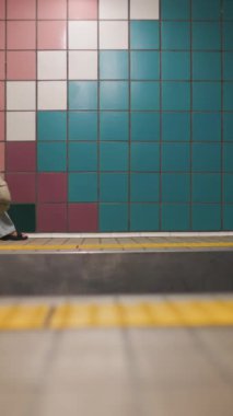 Dikey çekim. Sırt çantalı şık elbiseli genç bir kız metro istasyonuna girer, yere oturur ve treni bekler. Tren bekleyen bir kız. Metrodaki kız..