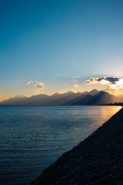 Akdeniz kıyılarının panoramik manzarası, gün batımında güzel dağlar. Panoramik günbatımı manzarası ve pitoresk plaj. Antalya. Türkiye.