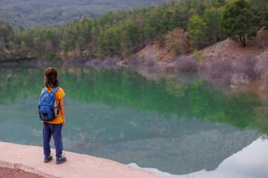 Yaz kampı. Sırt çantalı bir çocuk güzel bir dağ gölüne bakıyor. Bir dağ gölünün yanında yürüyüş. Çocuklarla Tatil