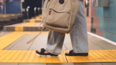 Çantası olan kız tren istasyonunda bekliyor. Moda çantaları yakın plan. Treni bekle. Metrodaki kız. Şık giyinmiş genç bir kız ve metroda çantası var. moda ve tarz.