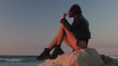 Kız gün batımına karşı özgür hissediyor. Genç kız sahilde dans ediyor. Sıradan moda, eğlenceli atmosfer..