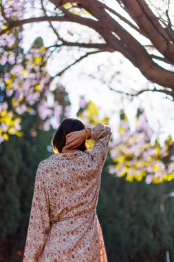 Şık bir yaz elbisesi içinde genç ve güzel bir kadın. Arkadan bak. Sokakta poz veren kaygısız bir kadın. Pozitif model yürüyüş yaparken eğleniyor. Neşeli ve mutlu.