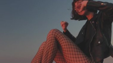 Kız gün batımına karşı özgür hissediyor. Genç kız sahilde dans ediyor. Sıradan moda, eğlenceli atmosfer..