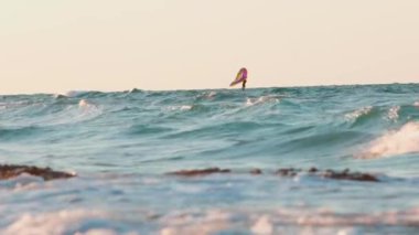 Bir adam, mavi bir okyanusta el bilgisayarı şişirilebilir kanatlar ve hidrofolyo sörf tahtaları kullanarak kanat çırpıyor. İsrail.