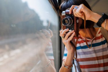 Tren yolculuğu. Genç bir kadın, elinde kamerayla tren yolculuğunun tadını çıkarıyor. Turist kamerada güzel turistik yerlerin fotoğraflarını çeker. Film kamerası. Kız film kamerası kullanıyor..