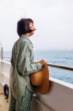 Yaz seyahati sırasında yolcu gemisinde tatil yapan bir kadın. Feribotun açık balkonunda dinlenen bir turistin silueti. Bir kız bir yolcu gemisinin güvertesinde durur ve denize bakar.