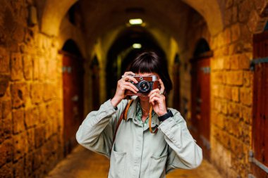 Şapkalı güzel bir kadın dışarıda analog kamera kullanarak fotoğraf çekiyor. Arap ülkelerine gitmek. seyahat ve tatil.