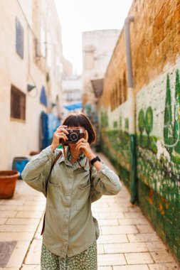 Kameralı kadın fotoğrafçı dışarıda fotoğraf çekiyor. Güzel bir kadın dışarıda analog kamera kullanarak fotoğraf çekiyor. Arap ülkelerine gitmek. seyahat ve tatil.