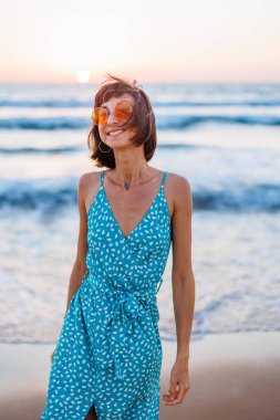 Mutlu kadın gülümsüyor ve sahilde eğleniyor. Genç ve güzel bir kızın yaz portresi. Güneş gözlüklü genç kız. Kız yaz tatilini denizde geçiriyor. Kumsalda dinlenmek..