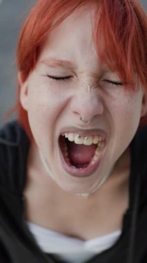 Dikey çekim. Kızgın ve çığlık atan genç bir kız. Bağıran üzgün kız, piercingli genç kız. Şok ve duygusal çöküntü, depresyon.