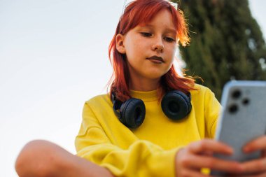 Şık bir genç arkadaşla sohbet ediyor. Genç bir kız telefonda mesaj yazıyor. Telefonu olan bir genç..