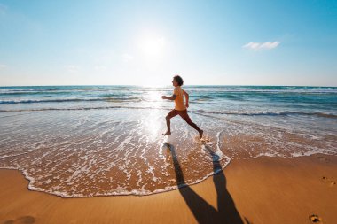 Adam deniz kıyısında çıplak ayakla koşuyor. Güçlü koşucu, hızlı koşu ve yaz antrenmanı. Genç bir erkek koşucu şafakta boş bir plaj boyunca koşar. Denize yakın koş..
