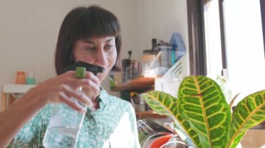 Çiçek sulayan bir kadın. Kız çiçeklerle, ev bahçesiyle ilgileniyor.