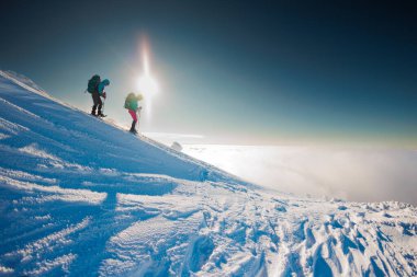 Dağcılar karda dağa tırmanırlar. Kış dağcılığı. Kar ayakkabılı iki kız karda yürür. Dağcılık ekipmanları. Kışın dağlarda yürüyüş..