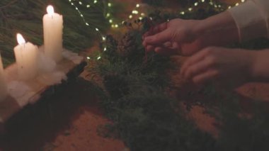 Yeni yıl kutlaması. Kış tatili Kadın eli Noel çelengini süslüyor. Bir kadın köknar dallarından Noel kompozisyonu yapar..