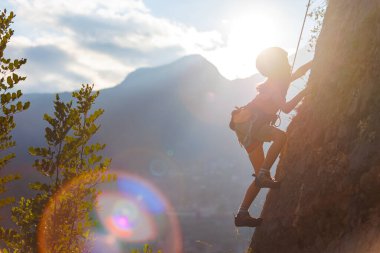Dağcı çocuk. Çocuk kaya tırmanışı çalışıyor. Yaz kampı. Doğada spor. Sevimli bir genç kayaya tırmanıyor, spor insanları yaşam tarzı konseptiyle.
